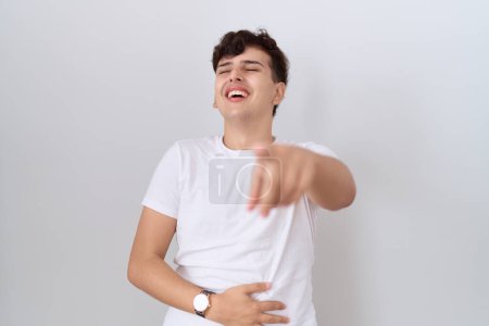 Téléchargez les photos : Jeune homme non binaire portant un t-shirt blanc décontracté se moquant de vous, pointant du doigt l'appareil photo avec la main sur le corps, expression de honte - en image libre de droit