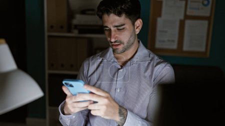 Téléchargez les photos : Jeune homme hispanique travailleur d'affaires en utilisant smartphone travaillant au bureau - en image libre de droit