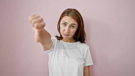 Téléchargez les photos : Jeune femme faisant signe négatif avec le pouce vers le bas sur fond rose isolé - en image libre de droit