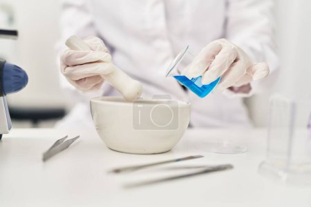 Photo for Young beautiful hispanic woman scientist pouring liquid on bowl at laboratory - Royalty Free Image