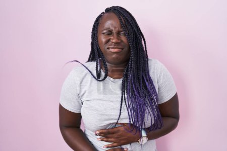 Téléchargez les photos : Jeune femme africaine debout sur fond rose avec la main sur le ventre parce que l'indigestion, la maladie douloureuse se sent mal. concept de douleur. - en image libre de droit
