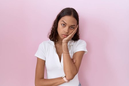 Téléchargez les photos : Jeune femme hispanique portant un t-shirt blanc décontracté pensant fatigué et ennuyé avec des problèmes de dépression avec les bras croisés. - en image libre de droit