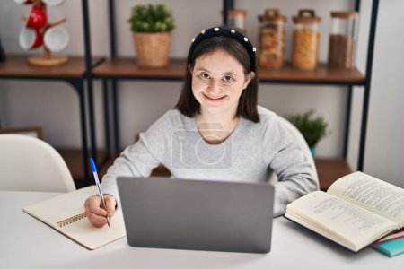 Photo for Young woman with down syndrome sitting on table studying at home - Royalty Free Image