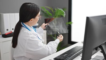 Foto de Mujer hispana joven doctora en cita online mostrando rayos X en la clínica - Imagen libre de derechos