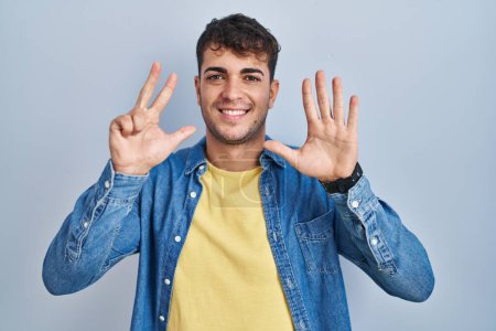 Téléchargez les photos : Young hispanic man standing over blue background showing and pointing up with fingers number eight while smiling confident and happy. - en image libre de droit