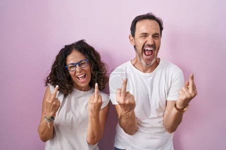Photo for Middle age hispanic couple together over pink background showing middle finger doing fuck you bad expression, provocation and rude attitude. screaming excited - Royalty Free Image