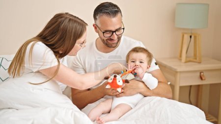 Téléchargez les photos : Famille de mère, père et bébé assis ensemble sur le lit dans la chambre - en image libre de droit