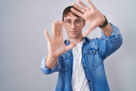 Photo for Caucasian blond man standing wearing glasses doing frame using hands palms and fingers, camera perspective - Royalty Free Image