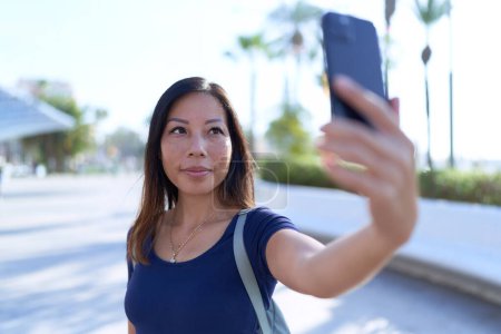 Foto de Joven mujer asiática sonriendo confiado haciendo selfie por el teléfono inteligente en el parque - Imagen libre de derechos