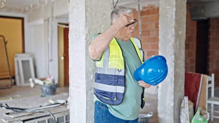 Foto de Constructor de hombre de pelo gris de mediana edad sudando en el sitio de construcción - Imagen libre de derechos