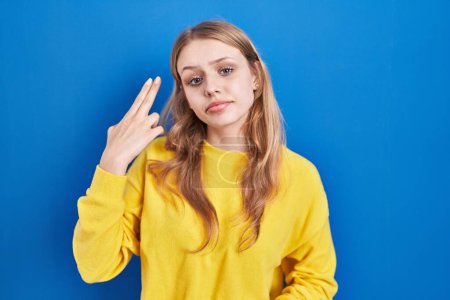 Foto de Young caucasian woman standing over blue background shooting and killing oneself pointing hand and fingers to head like gun, suicide gesture. - Imagen libre de derechos