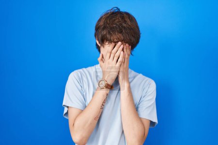 Téléchargez les photos : Hispanic young man standing over blue background rubbing eyes for fatigue and headache, sleepy and tired expression. vision problem - en image libre de droit