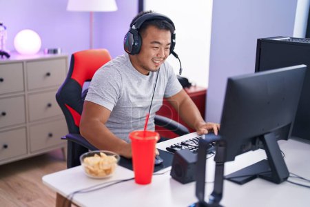 Téléchargez les photos : Young chinese man streamer playing video game using computer at gaming room - en image libre de droit