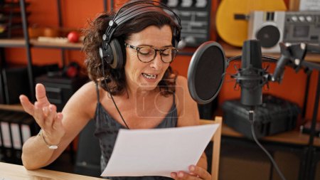 Téléchargez les photos : Moyen Age femme hispanique musicien souriant chanson de chant confiant au studio de musique - en image libre de droit