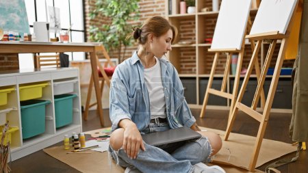 Photo for Young woman artist sitting on floor at art studio - Royalty Free Image