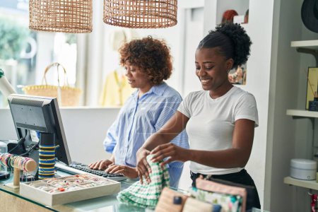Téléchargez les photos : Africaines américaines assistantes de magasin souriantes confiantes travaillant dans un magasin de vêtements - en image libre de droit