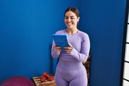 Photo for Young beautiful hispanic woman smiling confident using touchpad at sport center - Royalty Free Image