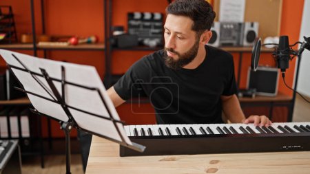 Foto de Joven músico hispano tocando el piano en el estudio de música - Imagen libre de derechos