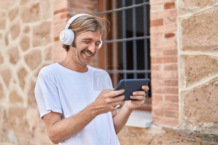 Téléchargez les photos : Young blond man smiling confident watching video on touchpad at street - en image libre de droit