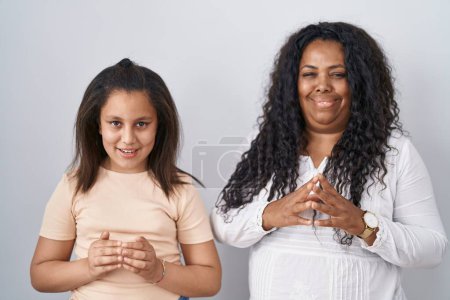 Photo for Mother and young daughter standing over white background hands together and fingers crossed smiling relaxed and cheerful. success and optimistic - Royalty Free Image