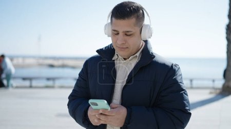 Foto de Joven hispano escuchando música en la playa - Imagen libre de derechos