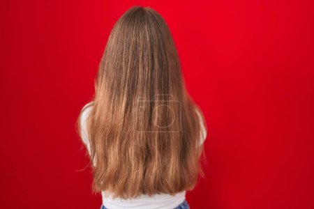 Photo for Young caucasian woman standing over red background standing backwards looking away with crossed arms - Royalty Free Image