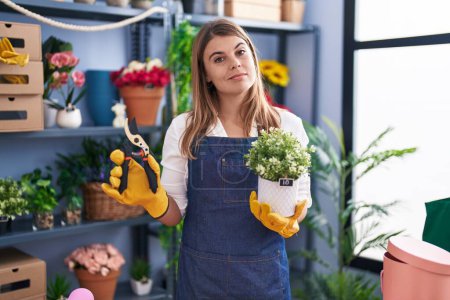 Photo for Young hispanic woman working at florist shop relaxed with serious expression on face. simple and natural looking at the camera. - Royalty Free Image
