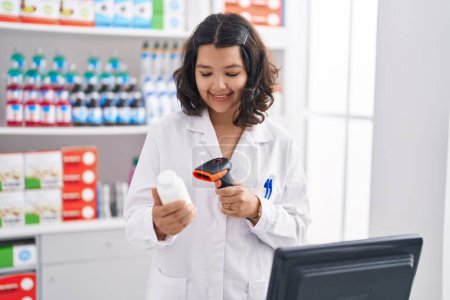 Foto de Joven mujer farmacéutico escaneo pastillas botella en la farmacia - Imagen libre de derechos