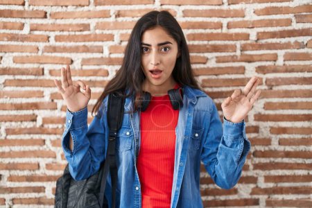 Photo for Young teenager girl wearing student backpack doing relax sign in shock face, looking skeptical and sarcastic, surprised with open mouth - Royalty Free Image