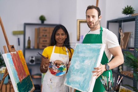Foto de Hombre y mujer artista pareja sosteniendo dibujo de lona en el estudio de arte - Imagen libre de derechos
