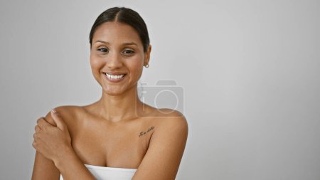 Foto de Joven latina sonriendo confiada tocando el brazo sobre fondo blanco aislado - Imagen libre de derechos