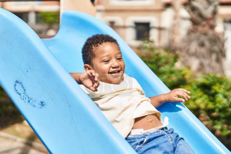 Téléchargez les photos : Enfant afro-américain jouant sur la glissière à l'aire de jeux - en image libre de droit