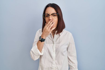 Foto de Young hispanic woman standing over white background bored yawning tired covering mouth with hand. restless and sleepiness. - Imagen libre de derechos