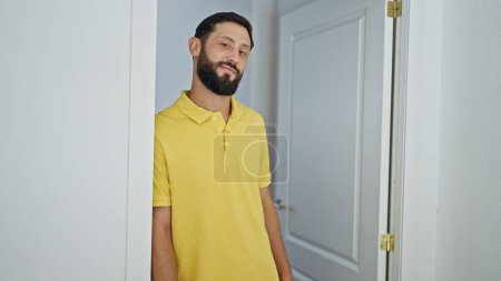 Foto de Joven hombre hispano apoyado en la puerta sonriendo en casa - Imagen libre de derechos