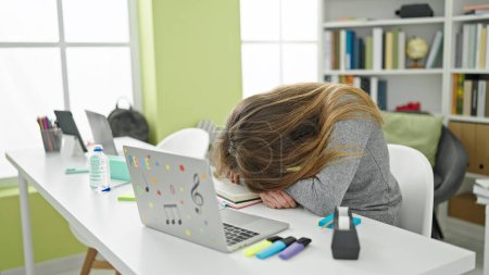 Téléchargez les photos : Jeune étudiante caucasienne dormant la tête sur la table à la bibliothèque de l'université - en image libre de droit