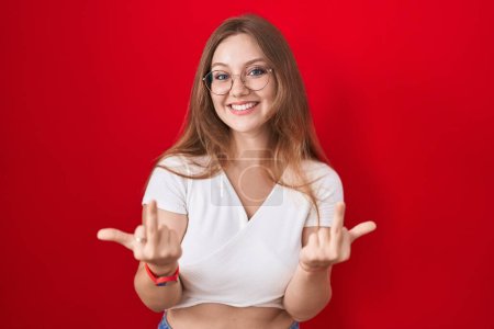 Téléchargez les photos : Young caucasian woman standing over red background showing middle finger doing fuck you bad expression, provocation and rude attitude. screaming excited - en image libre de droit