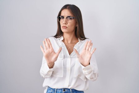 Photo for Young brunette woman wearing glasses moving away hands palms showing refusal and denial with afraid and disgusting expression. stop and forbidden. - Royalty Free Image
