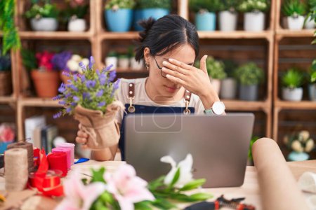 Photo for Young hispanic woman working at florist shop doing video call covering eyes with hand, looking serious and sad. sightless, hiding and rejection concept - Royalty Free Image