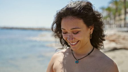 Téléchargez les photos : Jeune belle hispanique femme touriste souriant confiant portant bikini à la plage - en image libre de droit