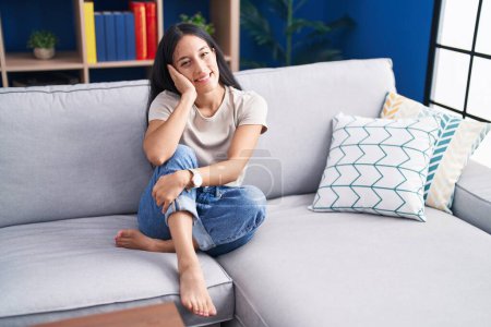 Téléchargez les photos : Jeune belle femme hispanique souriant confiant assis sur le canapé à la maison - en image libre de droit