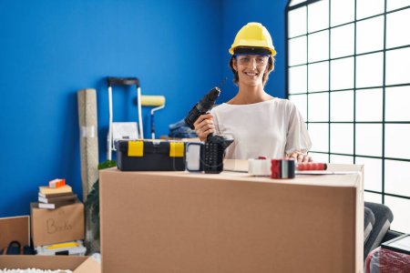 Photo for Brunette woman holding screwdriver at new home looking positive and happy standing and smiling with a confident smile showing teeth - Royalty Free Image