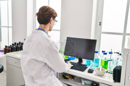 Téléchargez les photos : Jeune homme scientifique caucasien utilisant l'ordinateur au laboratoire - en image libre de droit
