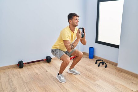Photo for Young hispanic man smiling confident using kettlebell training at sport center - Royalty Free Image