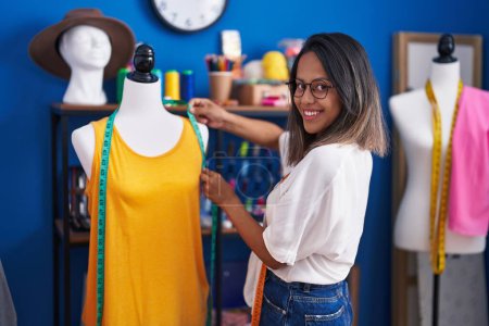 Photo for Young hispanic woman tailor smiling confident measuring t shirt at sewing studio - Royalty Free Image