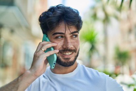 Photo for Young hispanic man smiling confident talking on the smartphone at street - Royalty Free Image