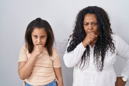 Foto de Madre e hija pequeña paradas sobre fondo blanco sintiéndose mal y tosiendo como síntoma de resfriado o bronquitis. concepto de atención sanitaria. - Imagen libre de derechos