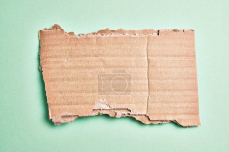 Foto de One ripped piece of cardboard material over isolated green background - Imagen libre de derechos
