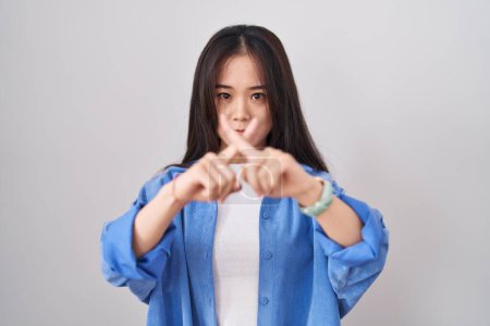 Téléchargez les photos : Jeune femme chinoise debout sur fond blanc expression de rejet croisant les doigts faisant signe négatif - en image libre de droit