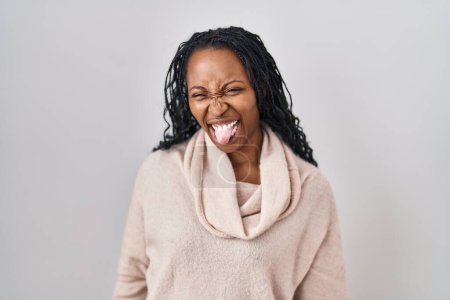 Téléchargez les photos : Femme africaine debout sur fond blanc langue collante heureux avec une expression drôle. concept d'émotion. - en image libre de droit