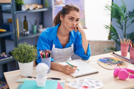 Photo for Young woman artist drawing on notebook with serious expression at art studio - Royalty Free Image